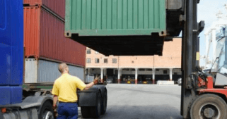 A man standing in front of metal shipping containers